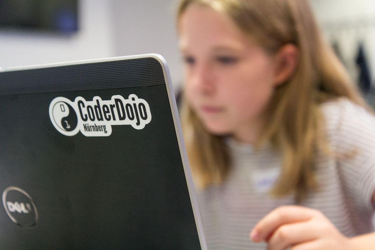 Girl working on a laptop with a CoderDojo sticker
