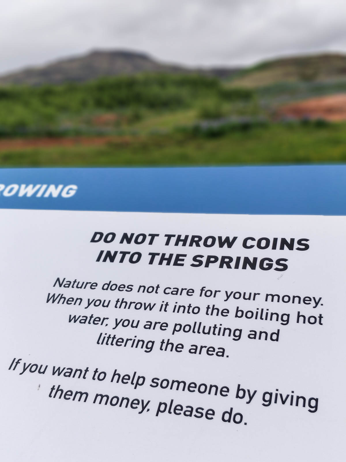 Schild: Do not throw coins into the springs. Nature does not care for your money. When you throw it into the boiling hot water, you are polluting and littering the area. If you want to help someone by giving them money, please do.