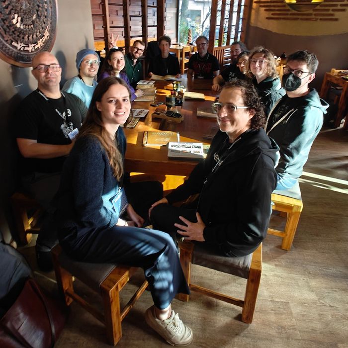 12 Personen um einen großen Tisch, in Erwartung ihrer Speisen und Getränke