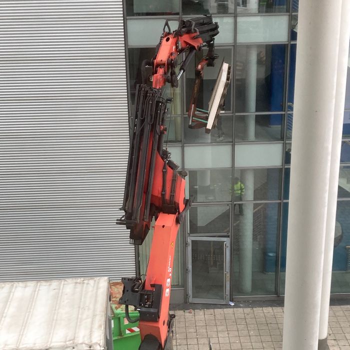 Ein Cherry Picker liefert ein großes Paket durch ein Fenster im oberen Stockwerk