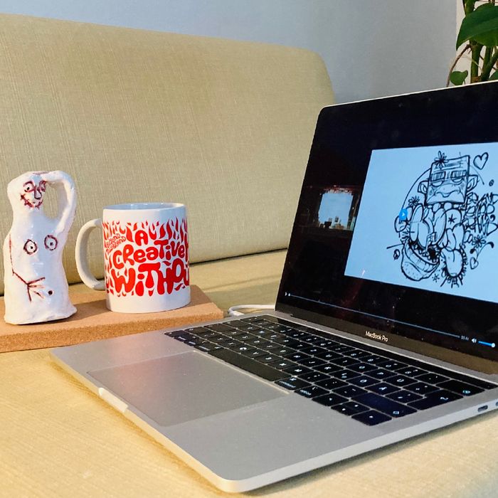 Ein Laptop auf dem Sofa, daneben eine Beyond Tellerrand Tasse und eine weiße Tonfigure, die Ähnlichkeit mir einem Geist hat.