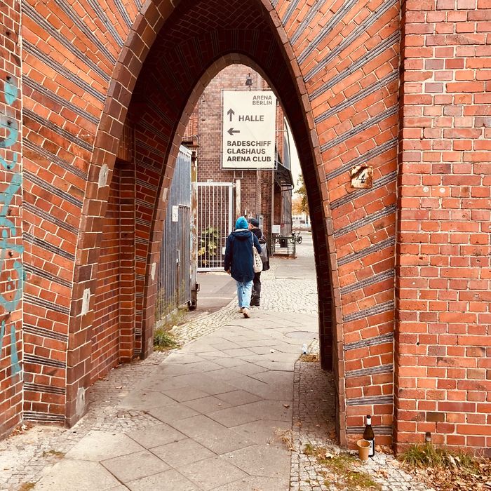 Joschi und Jakob auf dem Weg zum Festsaal Kreuzberg. Die Gebäude sind aus Backstein, davor ein Torbogen.