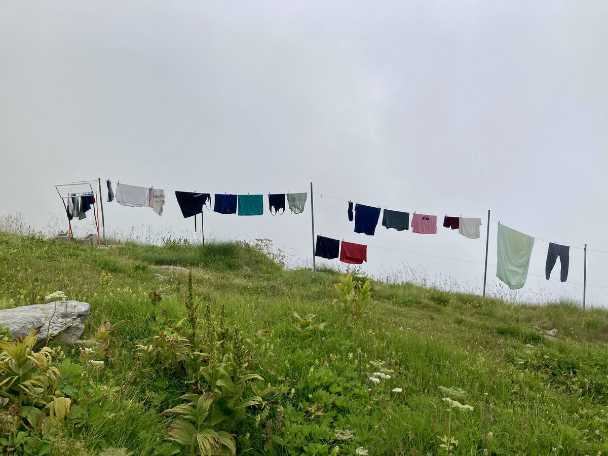 Eine Leine mit bunten Wäschestücken an einem Berghang, im Hintergrund ist der Himmel grau