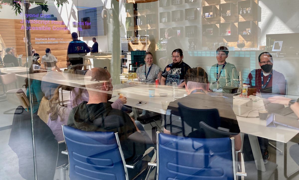 Blick in einen verglasten Workshopraum mit Teilnehmenden. Auf der Scheibe sieht man Spiegelungen.