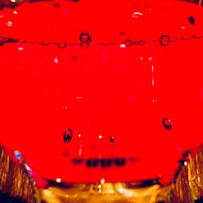 Ein Glas mit Sprudelwasser vor rotem Hintergrund.