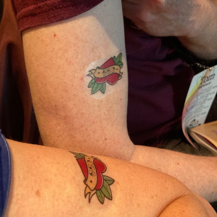 2 Oberarme mit einem Tatto, das als Motiv ein Herz zeigt, auf dem CSS steht