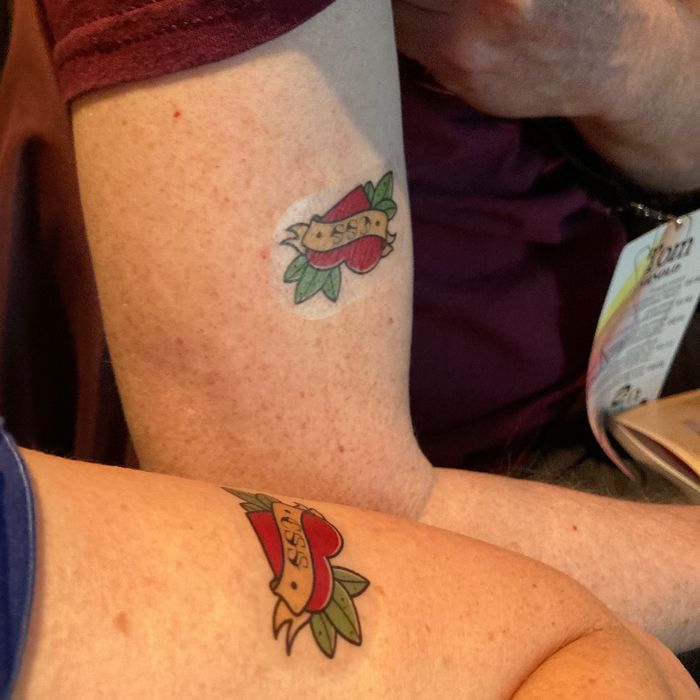 2 Oberarme mit einem Tatto, das als Motiv ein Herz zeigt, auf dem CSS steht