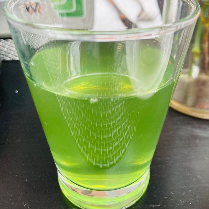 Ein Glas mit einem grünlichen Getränk.