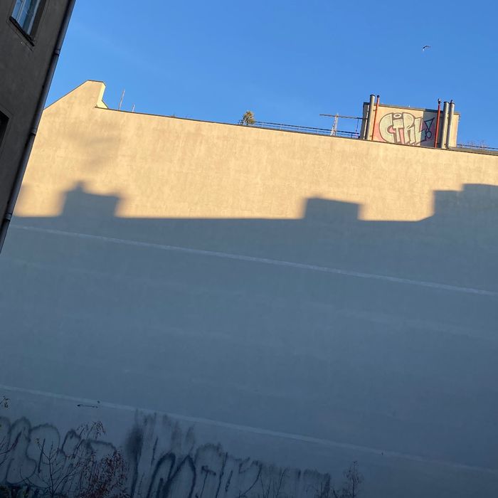 Blick auf eine Hauswand mit dem Schatten eines anderen Hauses. Blauer Himmel