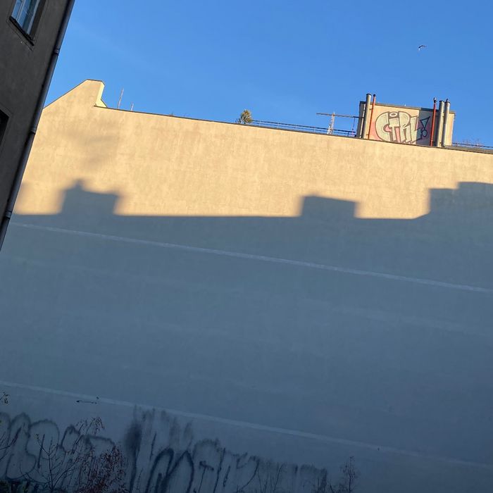 Blick auf eine Hauswand mit dem Schatten eines anderen Hauses. Blauer Himmel