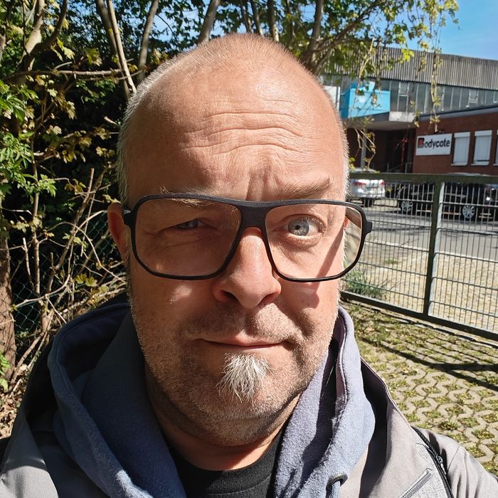 Selfie von Joschi vor dem Tollwerk-Büro. Die Sonne scheint in sein Gesicht, er hat die linke Augenbraue hochgezogen.