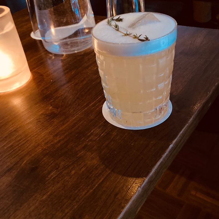 Ein Cocktail steht auf einem Holztisch, angeschnitten ist eine Kerze zu sehen