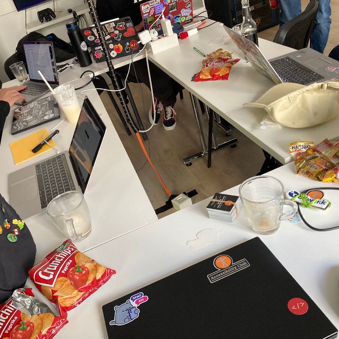 Blick von oben auf Tische mit aufgeklappten Laptops, leeren Chipstüten und vielen kleinen Tüten mit Gummibärchen