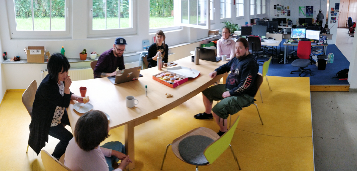 Umi, Kumiko, Nico, Nina, Annika und Kai beim Planen am Esstisch. Jeff hat eine Schachtel mit Donuts mitgebracht.