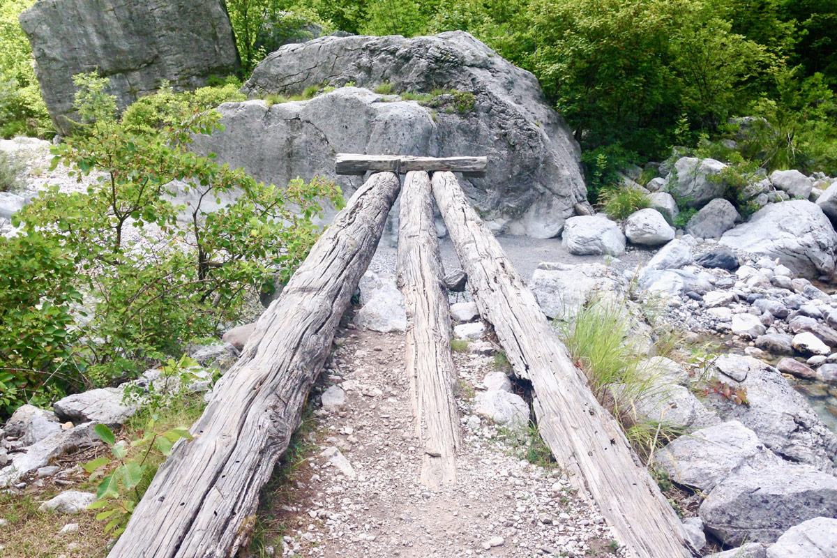 Drei Baumstämme zeigen Richtung Mitte eines Bergbachs, den Abschluß bildet ein Querstück