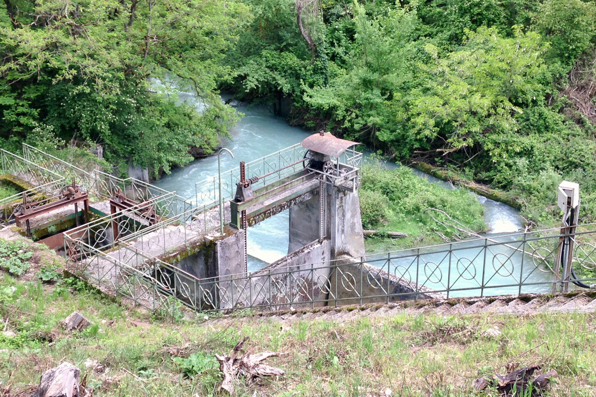 Blick von leicht erhöhter Position auf ein altes Wasserkraftwerk an einem Fluß