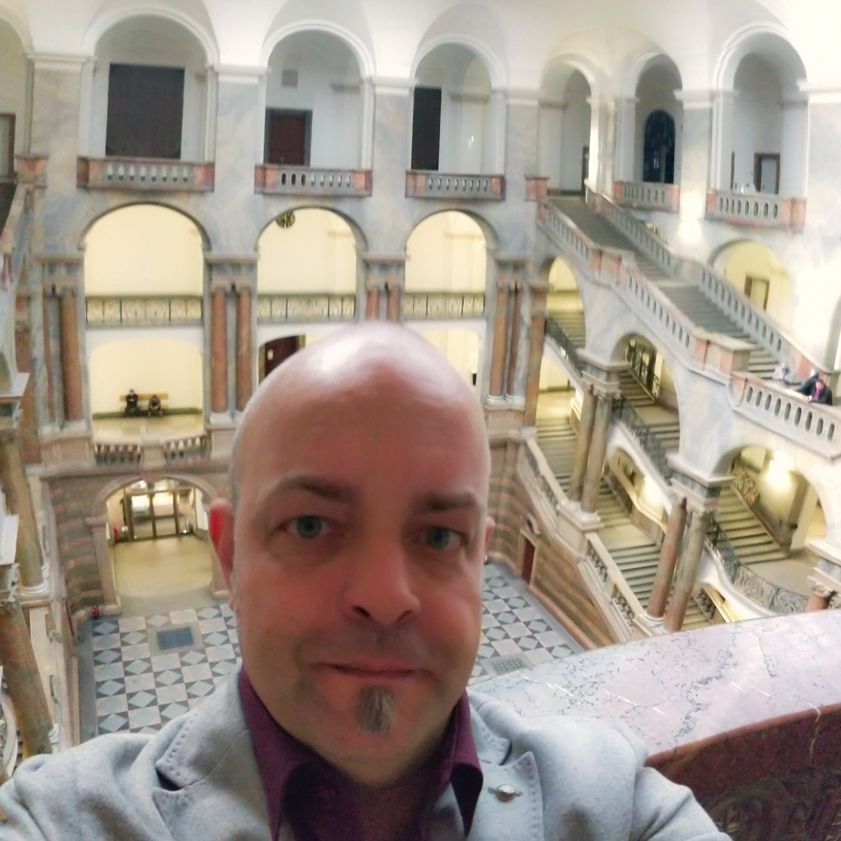 Selbstportrait von Joschi vor der Kulisse der Empfangshalle des neobarocken Justizpalastes München