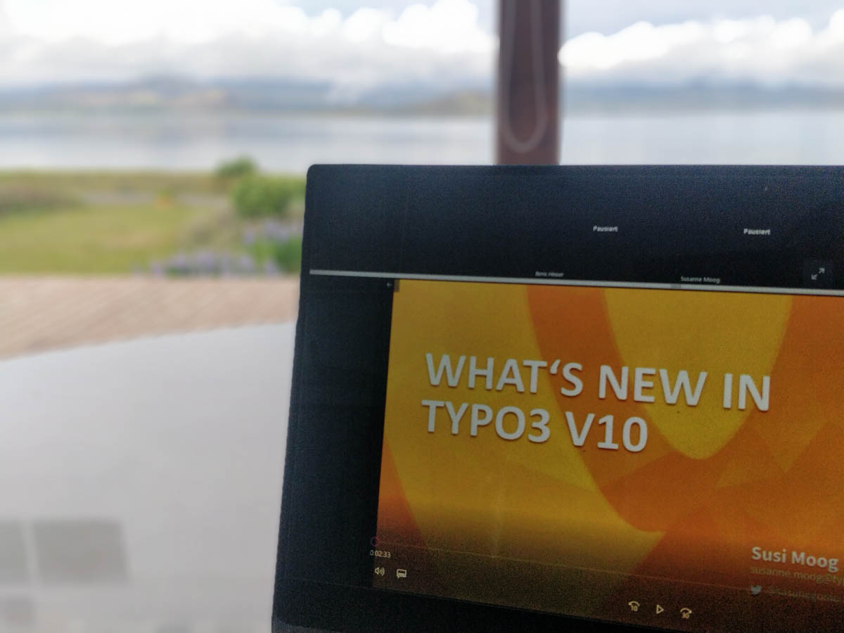 Laptop mit TYPO3-Onlineseminar auf dem Bildschirm, im Hintergrund der See