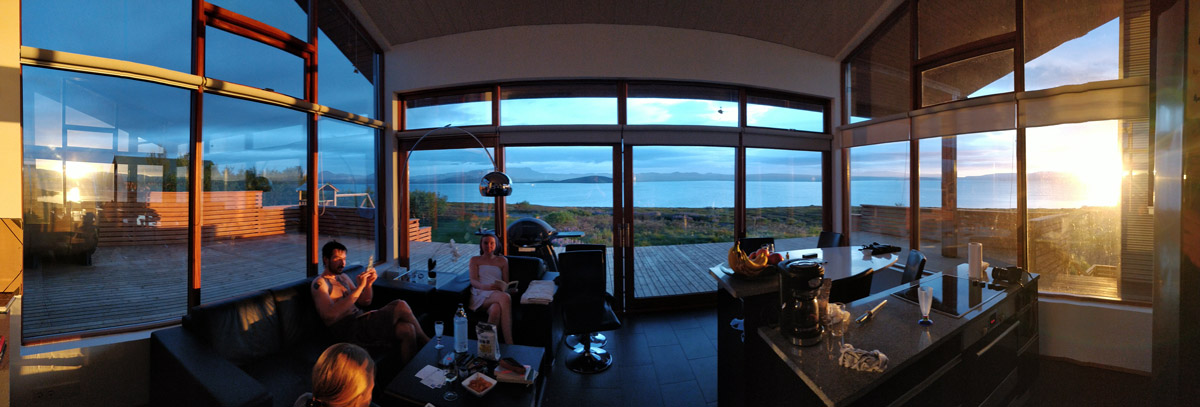 180°-Panorama um Mitternacht aus dem rundum verglasten Sommerhaus, Sonnenuntergangslicht und Blick über den See