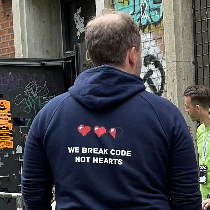 Rückansicht eines Mannes mit einem Hoodie mit der Aufschrift „We break code not hearts“